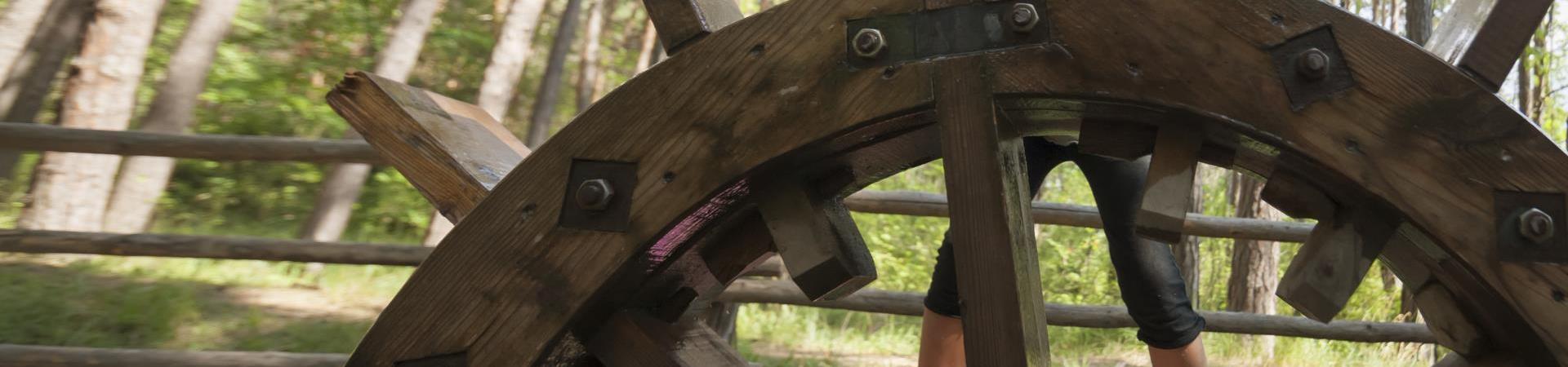 A kid next to a water wheel
