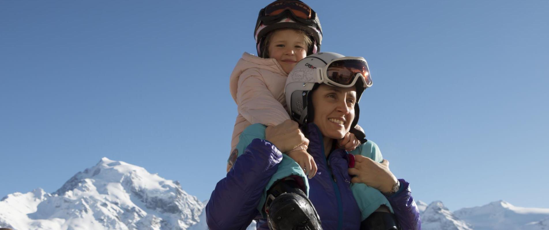 Una donna porta una bambina sulle spalle